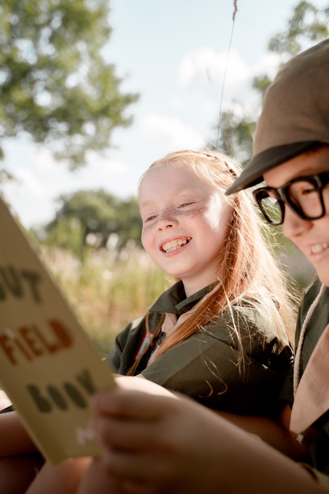 boy and girl looking at book and smiling on summer camp holiday